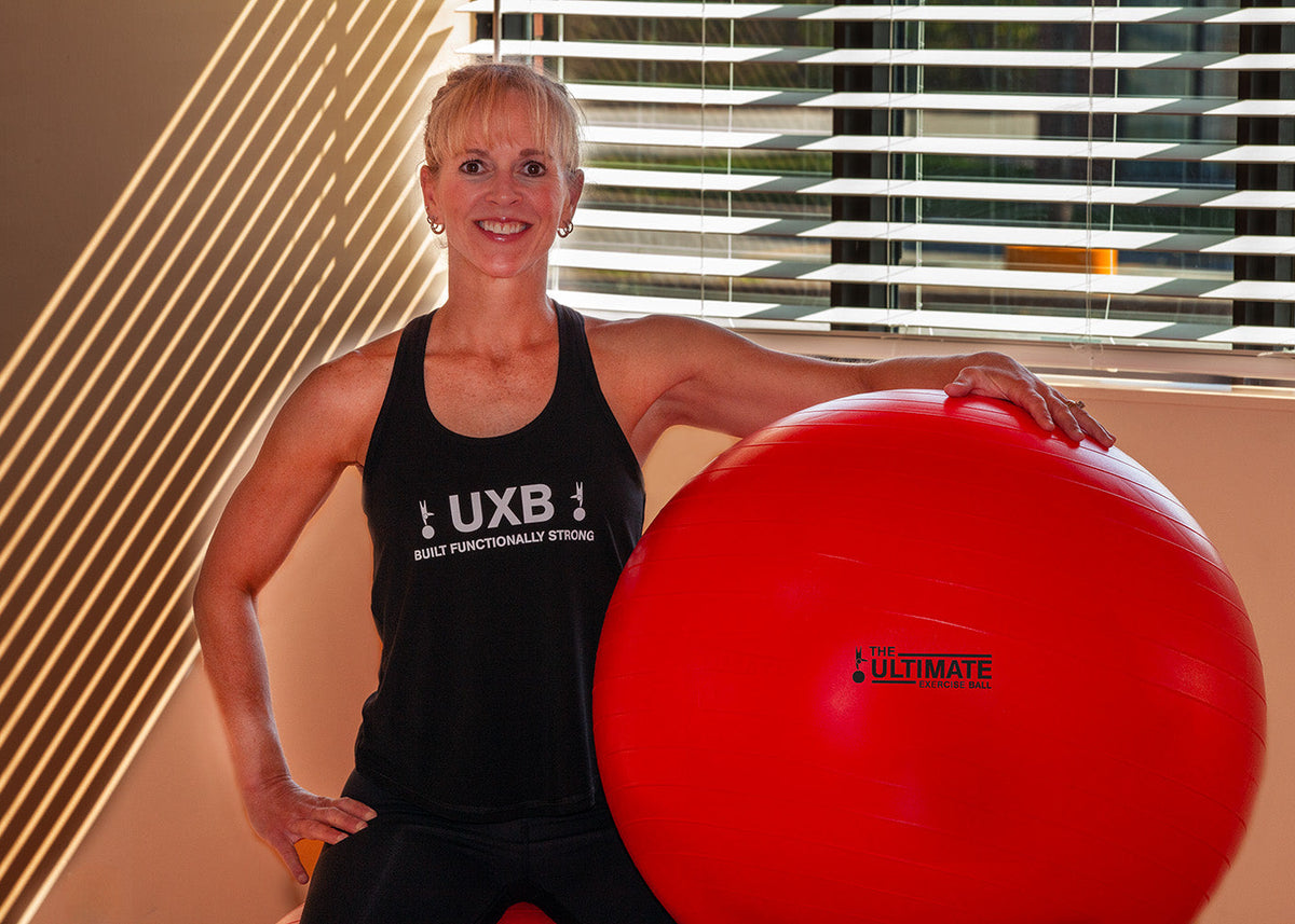 Sports Therapist holding a big red exercise ball by her side
